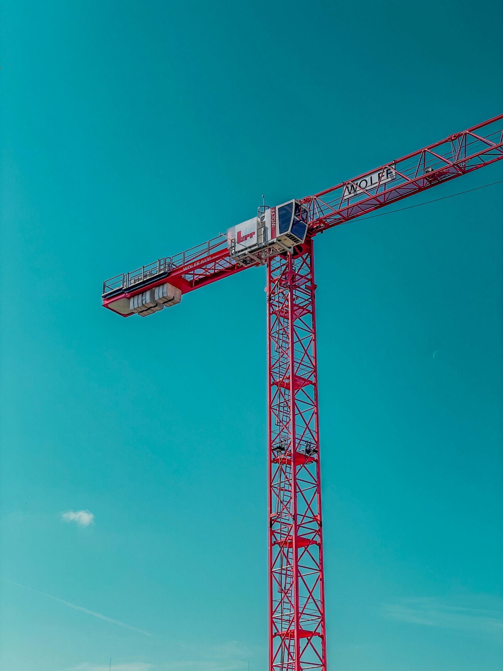 a large red crane sitting on top of a lush green field